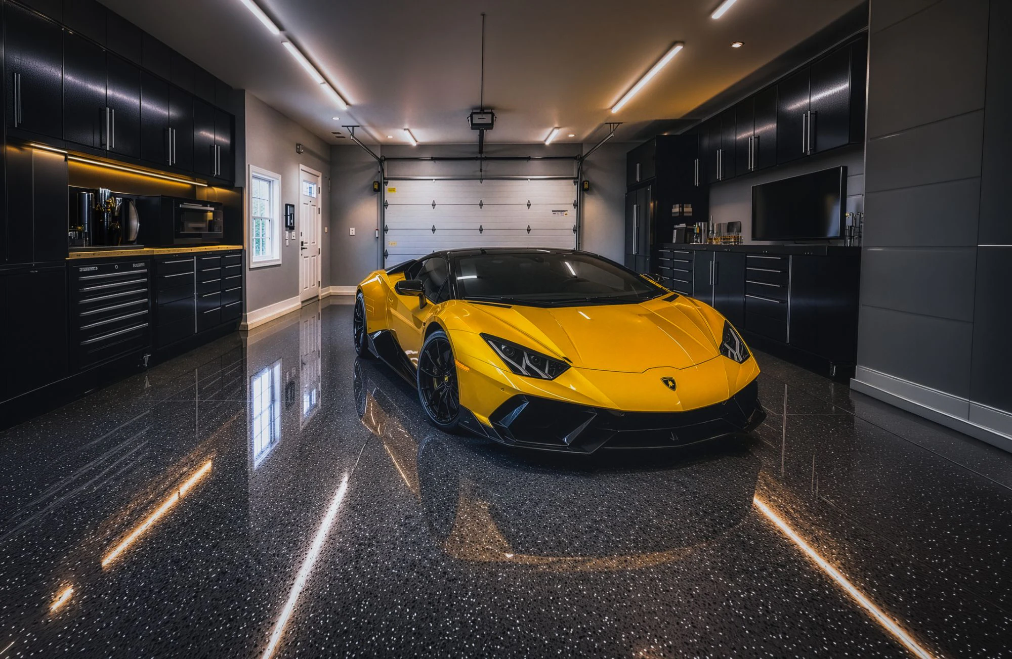 A yellow supercar parked on a glossy, speckled dark garage floor between walls of black cabinetry, the ceiling lights reflected in the finish.